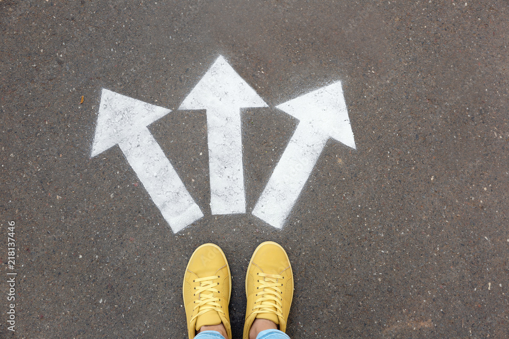 Woman standing near arrows on asphalt, top view. Choice concept